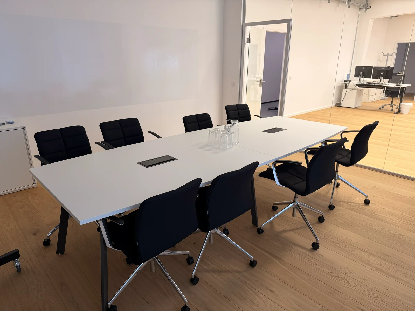 Sauberer Besprechungsraum mit Konferenztisch und angrenzendem Bürobereich